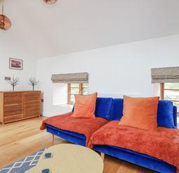 A living room with a blue sofa and a wooden sideboard at The Old Dairy in 