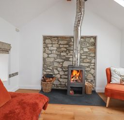 A snug with a wood stove and chair at The Old Dairy in 