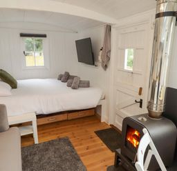 A sleeping area with a bed and stove at Shepherd's Hut in Perranarworthal