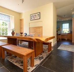 A dining room with a wooden table and benches at The Old Vicarage in St Issey