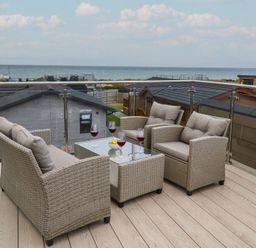 An outdoor seating area with drinks and a sea view at Lodge 1 Norwich