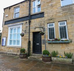 A front view of a stone building with a door and windows at The Railway Apartment in Hexham