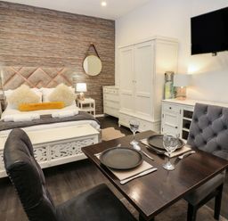 A bedroom with a dining area and a television at The Railway Apartment in Hexham
