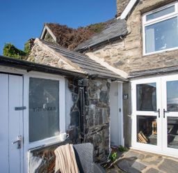 An outdoor view of The Ingle with stone walls and doors in Barmouth