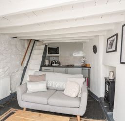 A living room with a sofa and kitchen area at The Ingle in Barmouth