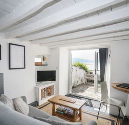 A living room with a sofa, television, and coffee table at The Ingle in Barmouth