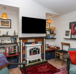 A living room with a television and bookshelf at Moon Cottage White Cross Bay Holiday Park near Troutbeck Bridge