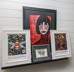 Artworks on a shelf including portraits and nature-themed prints at Moon Cottage White Cross Bay Holiday Park near Troutbeck Bridge