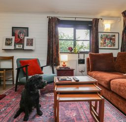 A living room with a dog sitting on the floor at Moon Cottage in White Cross Bay Holiday Park near Troutbeck Bridge
