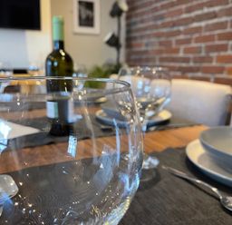 A dining table set with glasses and a wine bottle at Dolwen in Caernarfon