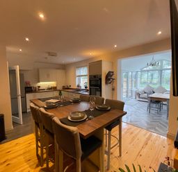 A kitchen with a dining table and bar stools at Dolwen, Caernarfon