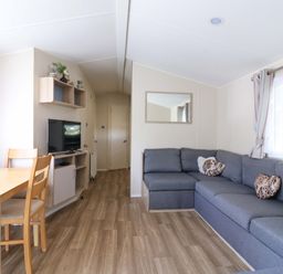 A living room with a sofa and dining area at Singh and Leite Family Caravan St. Osyth