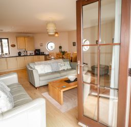 A living room with a sofa and kitchen area at Awel y Môr in Burry Port