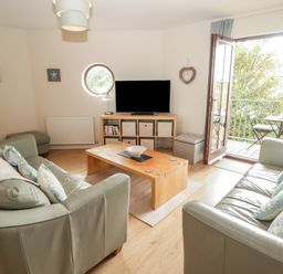 A living room with a television and sofas at Awel y Môr in Burry Port
