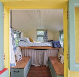 A sleeping area with a bed and bench at Prudence in Panson Mill near Ashwater