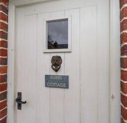 A door with a lion knocker and a name plate at Bubbs Cottage