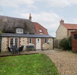An outdoor view of a house with a garden and seating area at Bubbs Cottage 