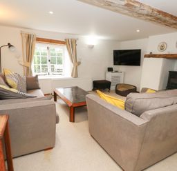A living room with a sofa, coffee table, and television at Bubbs Cottage