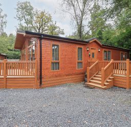 A wooden cabin with a deck and steps at Laughing Duck in Troutbeck Bridge