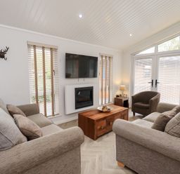 A living room with a sofa and television at Laughing Duck in Troutbeck Bridge