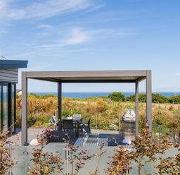 An outdoor area with a table and chairs under a pergola at Costal Lodge at Seaham Hall Seaham