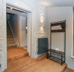 A hallway with stairs and a shelf at 3 bed property
