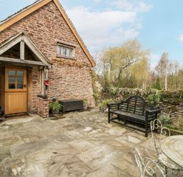 An outdoor patio with a stone wall and bench at a 1 bed property in Usk