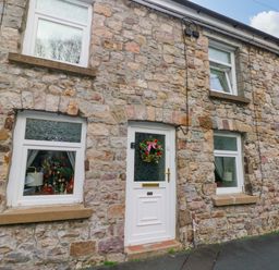 An outdoor view of a stone cottage with a front door and windows at Tawe Cottage Swansea