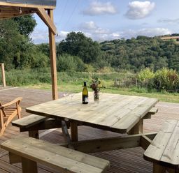 A table with chairs and a bottle on a deck at Treovis Cottage in Callington