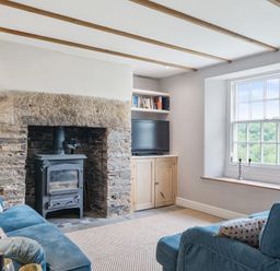 A living room with a fireplace and wood stove at Treovis Cottage in Callington