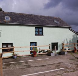 An outdoor area with a building and fence at The Milking Shippon at Thorne Langtree near Great Torrington