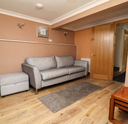 A living room with a sofa and footstool at Ty Cerrig apartment