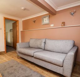 A living room with a sofa and clock at Ty Cerrig apartment