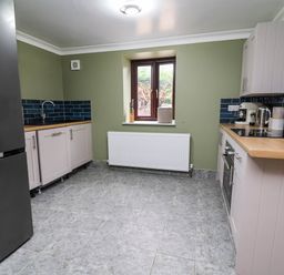 A kitchen with a refrigerator and sink at Ty Cerrig apartment