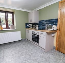 A kitchen with cabinets and appliances at Ty Cerrig apartment