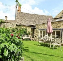 A garden with a bench and table at The Coach House in Burford