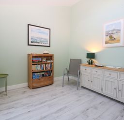 A room with a bookshelf and a chair at 2 Lon Y Dryw in Trearddur Bay
