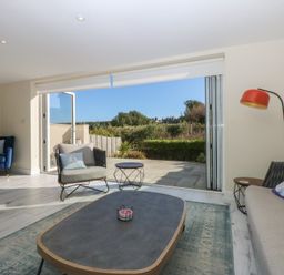A living room with a sliding door leading to outdoor space at 2 Lon Y Dryw in Trearddur Bay