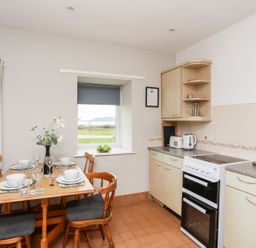 A kitchen with table and chairs at Ceiriad - 9 Ty'n Don near Llanengan