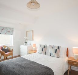 A bedroom with a bed, lamps, and a chair at Ceiriad - 9 Ty'n Don in Llanengan near Abersoch