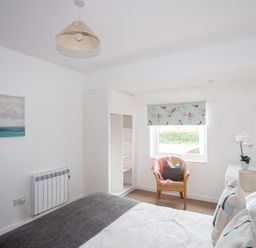 A bedroom with a bed and chair at Ceiriad - 9 Ty'n Don Llanengan near Abersoch