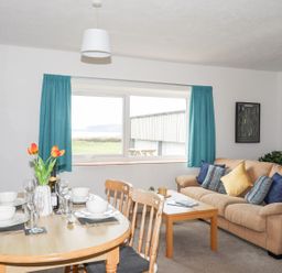 A living room with a table and chairs, and a couch at Oer - 8 Ty'n Don Llanengan near Abersoch