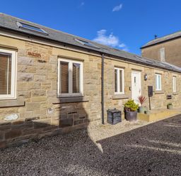 An outdoor area with stone walls and gravel at Hideaway Cottage No 1 in Seahouses