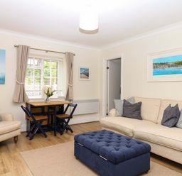 A living room with a sofa, armchair, and dining table at 2 Sheplegh Court in Blackawton near Dartmouth