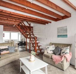 A living room with sofas and a staircase at Penrhyn - 4 Ty'n Don
