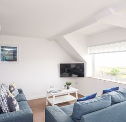 A living room with a TV and a coffee table at Towyn - 7 Ty'n Don