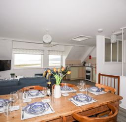 A dining area with a table set for meals and kitchen furnishings at Towyn - 7 Ty'n Don