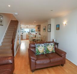 A living room with a staircase and kitchen view at 20 Heath Court in Brixham