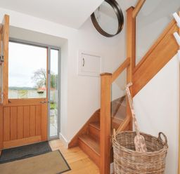 An entrance hall with a staircase and front door at The Dairy in 
