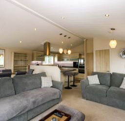 A living room with a kitchen area and seating at The Hideaway in Pwllheli